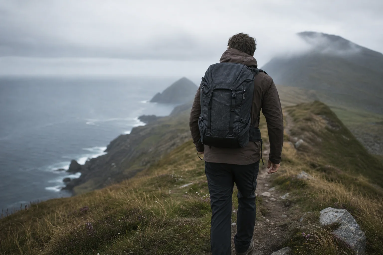 QLUNARA technischer Wanderrucksack auf einer nebligen Küstenroute